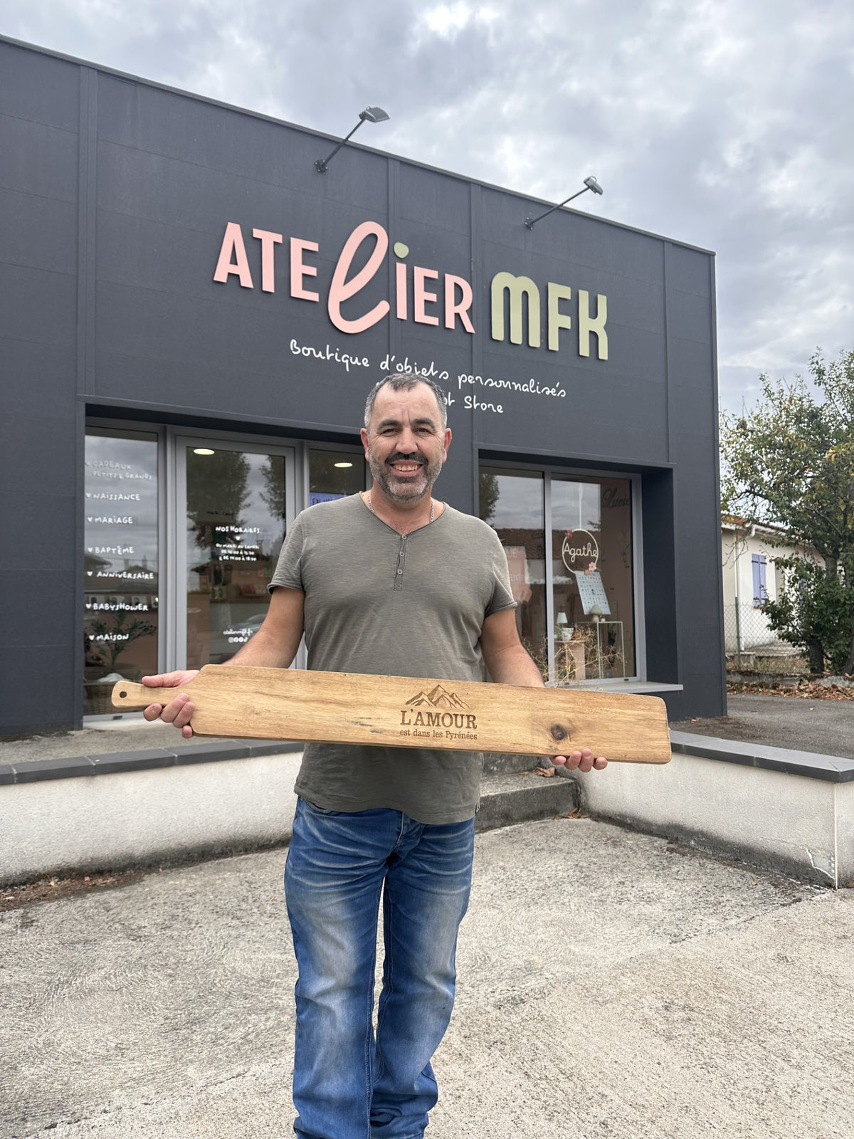 Jean-François Arabeyre devant la boutique Atelier MFK avec sa planche à découper en bois gravée